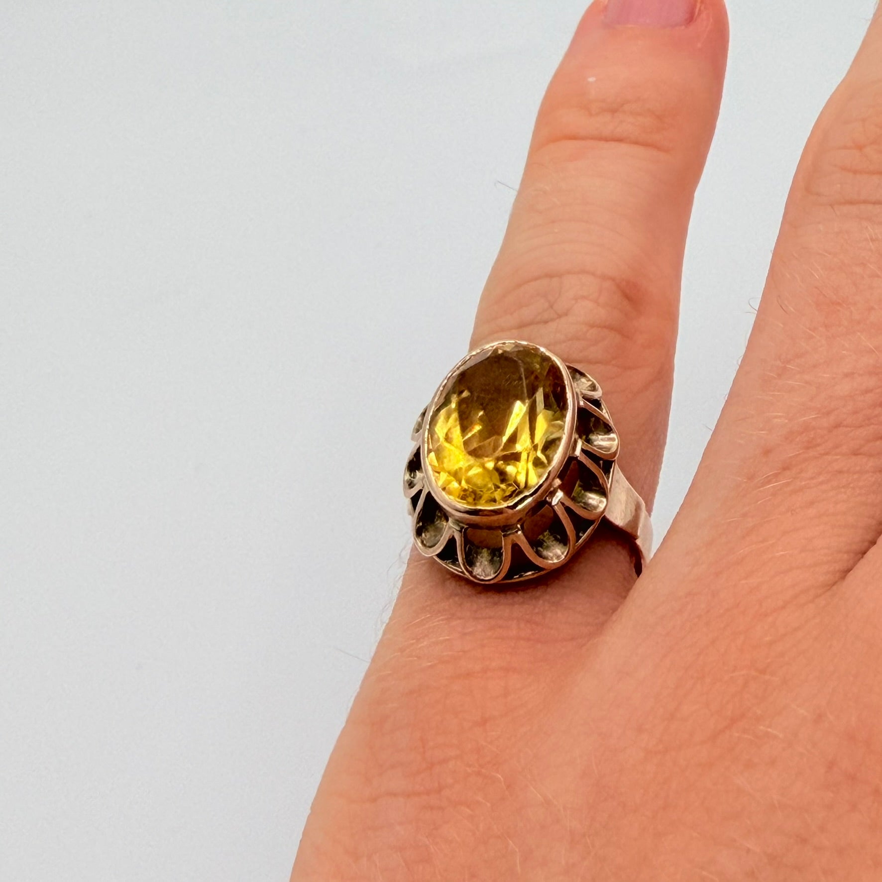 Goldring mit ovalem Citrin und filigraner Fassungsumrandung, Handansicht.