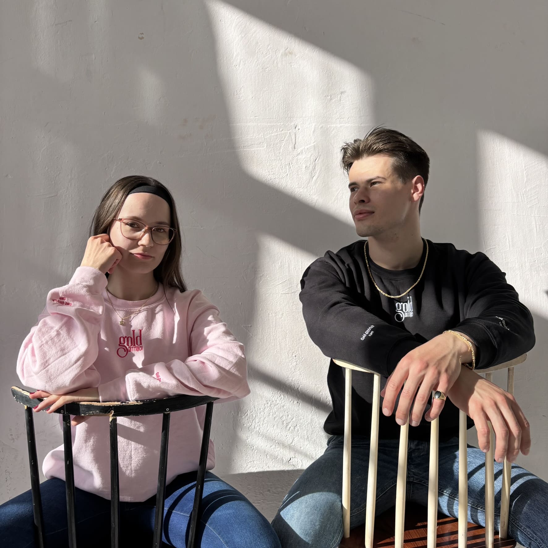 Imagebild von Gold Dittrich mit zwei Models im Sonnenlicht – sie tragen hochwertigen Schmuck aus Gold und Silber sowie Logo-Sweater der Marke.