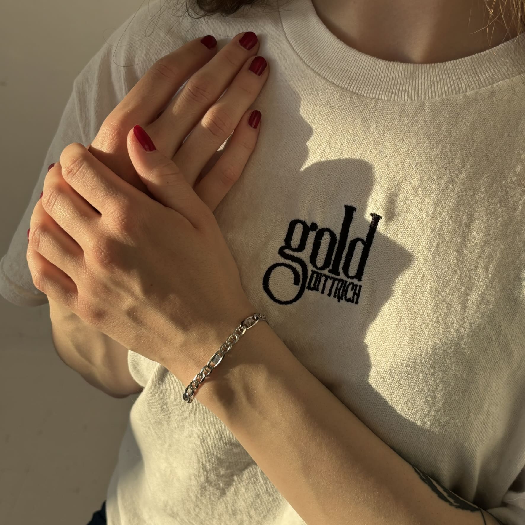 Frau mit weißem Gold Dittrich Shirt und rotem Nagellack trägt ein rhodiniertes Panzer-Steg-Armband aus 925 Sterling Silber – glänzendes Silberarmband mit Karabinerverschluss in elegantem Design.