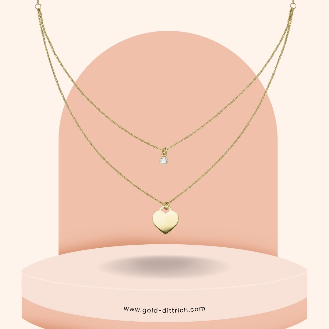 Zweireihiges Collier aus vergoldetem 925 Silber mit Herzanhänger und Zirkonia – elegante Detailansicht auf roséfarbenem Hintergrund