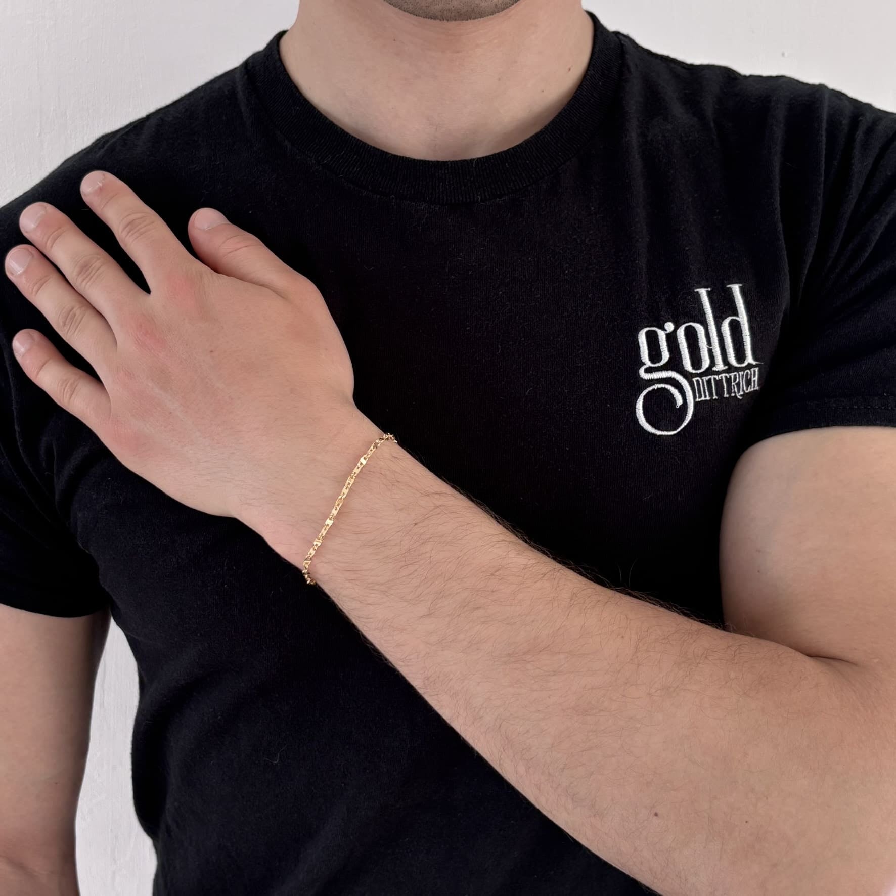 Mann mit schwarzem Gold Dittrich Shirt trägt ein filigranes Armband aus 585er Gelbgold in klassischer Panzerkettenoptik – ca. 19 cm lang, glänzend poliert und mit Karabinerverschluss.
