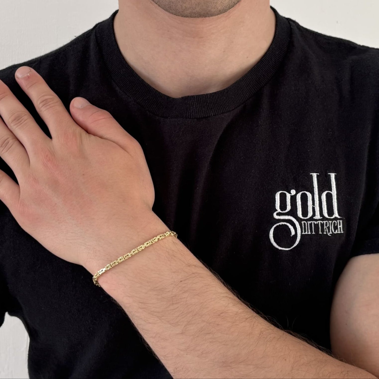 Mann mit schwarzem Gold Dittrich Shirt trägt ein massives Königsarmband aus 333er Gelbgold mit ca. 19 cm Länge – eleganter Herrenschmuck mit Karabinerverschluss in klassischem Design.
