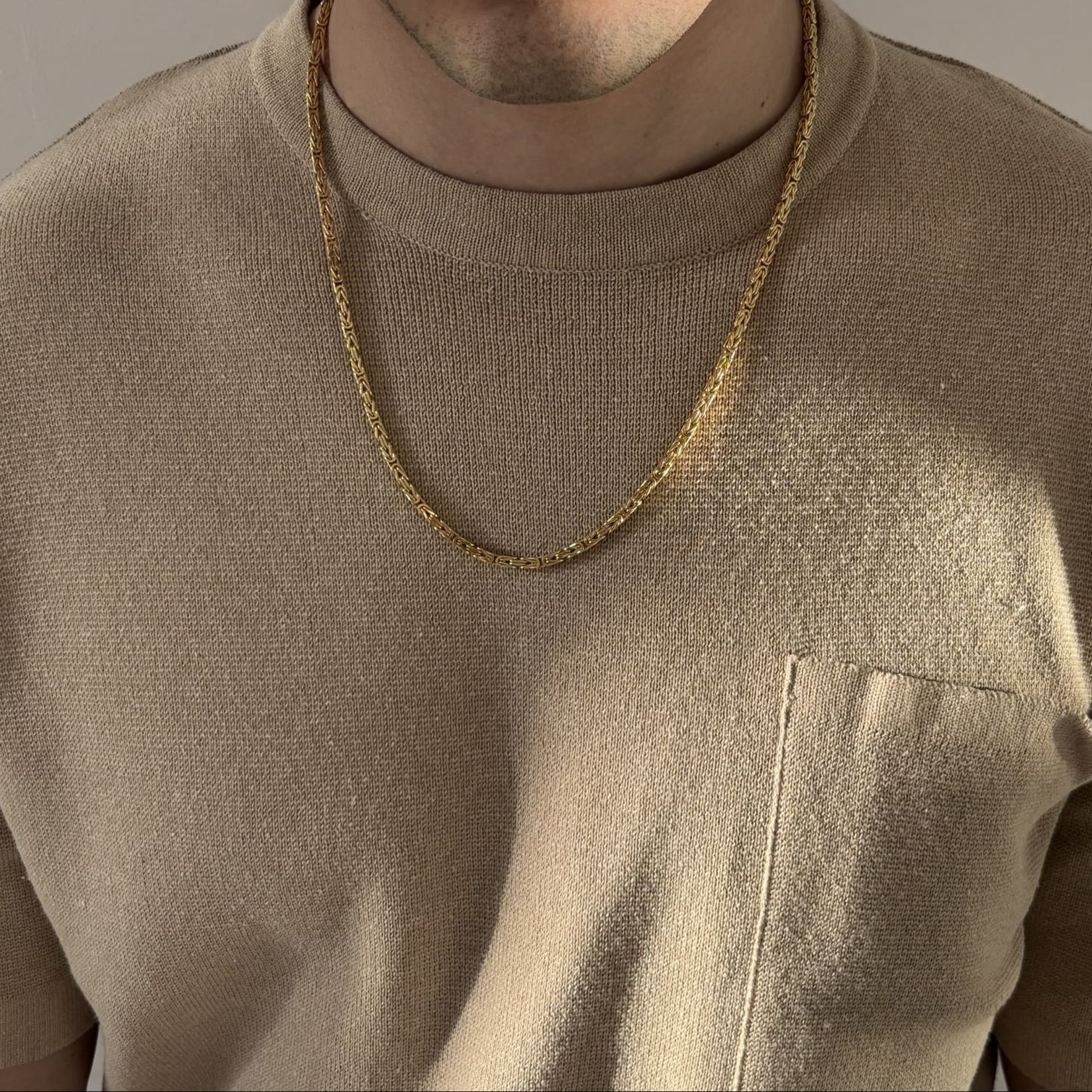 Mann mit beigefarbenem Shirt trägt eine vergoldete Königskette aus 925 Sterling Silber mit diamantierter Oberfläche – massiver Herrenschmuck mit ca. 60 cm Länge, stilvoll präsentiert von Gold Dittrich.